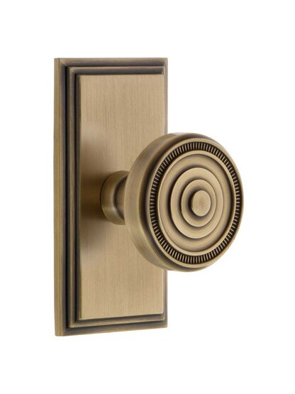 Grandeur Carre Rosette Door Set with Soleil Knobs in Antique Brass.